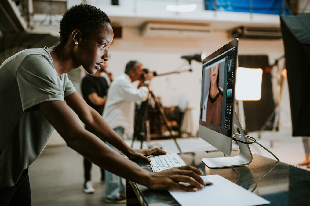 A graphic designer edits photos on a computer at a professional photography studio shoot.